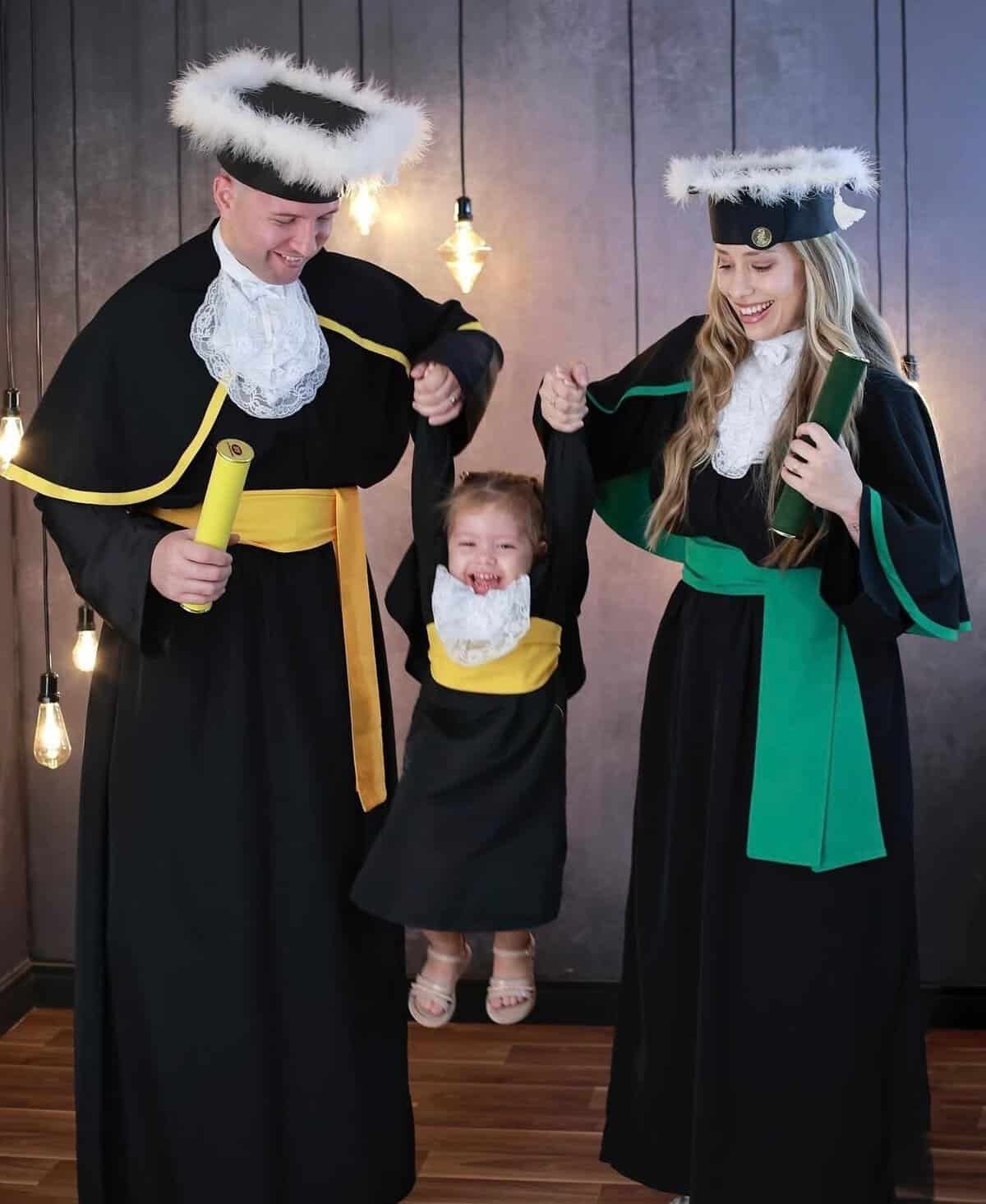 Família comemorando formatura com togas e capelos em ambiente acolhedor.